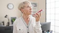 Middle age blonde woman business worker sending voice message by smartphone at office Royalty Free Stock Photo