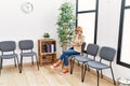 Middle age blonde woman desperate sitting on chair at waiting room Royalty Free Stock Photo