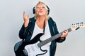 Middle age blonde woman playing electric guitar doing horns sign with fingers looking at the camera blowing a kiss being lovely Royalty Free Stock Photo