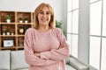 Middle age blonde woman smiling happy standing with arms crossed gesture at home Royalty Free Stock Photo
