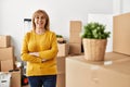 Middle age blonde woman standing with arms crossed gesture at new home Royalty Free Stock Photo