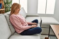 Middle age blonde woman using laptop sitting on the sofa at home Royalty Free Stock Photo