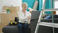 Middle age blonde woman using laptop sitting on sofa at new home Royalty Free Stock Photo