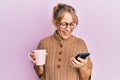 Middle age blonde woman using smartphone and drinking a cup of coffee celebrating crazy and amazed for success with open eyes Royalty Free Stock Photo