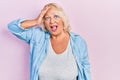Middle age blonde woman wearing casual clothes surprised with hand on head for mistake, remember error Royalty Free Stock Photo