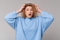Middle age blonde woman wearing casual sweatshirt upset by loss something, standing over light grey background. Confused disturbed