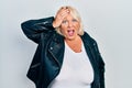 Middle age blonde woman wearing leather jacket surprised with hand on head for mistake, remember error Royalty Free Stock Photo
