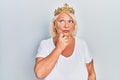 Middle age blonde woman wearing queen crown serious face thinking about question with hand on chin, thoughtful about confusing Royalty Free Stock Photo