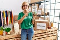 Middle age blonde woman wearing volunteer t shirt holding charity money smiling happy pointing with hand and finger