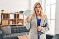 Middle age blonde woman working at therapy consultation office holding money afraid and shocked with surprise and amazed Royalty Free Stock Photo