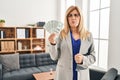 Middle age blonde woman working at therapy consultation office holding money puffing cheeks with funny face Royalty Free Stock Photo