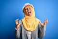 Middle age brunette architect woman wearing muslim traditional hijab and security helmet crazy and mad shouting and yelling with Royalty Free Stock Photo