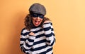 Middle age brunette burglar woman wearing mask and cap standing over yellow background celebrating surprised and amazed for Royalty Free Stock Photo