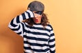 Middle age brunette burglar woman wearing mask and cap standing over yellow background peeking in shock covering face and eyes Royalty Free Stock Photo