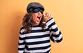 Middle age brunette burglar woman wearing mask and cap standing over yellow background shouting and screaming loud to side with Royalty Free Stock Photo