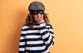 Middle age brunette burglar woman wearing mask and cap standing over yellow background thinking concentrated about doubt with Royalty Free Stock Photo