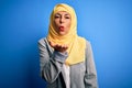 Middle age brunette business woman wearing muslim traditional hijab over blue background looking at the camera blowing a kiss with Royalty Free Stock Photo