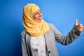 Middle age brunette business woman wearing muslim traditional hijab over blue background Looking proud, smiling doing thumbs up Royalty Free Stock Photo