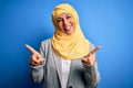 Middle age brunette business woman wearing muslim traditional hijab over blue background smiling confident pointing with fingers Royalty Free Stock Photo