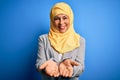 Middle age brunette business woman wearing muslim traditional hijab over blue background Smiling with hands palms together Royalty Free Stock Photo