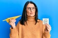 Middle age brunette woman holding email symbol and paper plane looking at the camera blowing a kiss being lovely and sexy