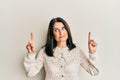 Middle age brunette woman pointing up with fingers smiling looking to the side and staring away thinking Royalty Free Stock Photo