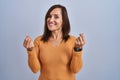 Middle age brunette woman standing wearing orange sweater doing money gesture with hands, asking for salary payment, millionaire Royalty Free Stock Photo