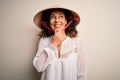 Middle age brunette woman wearing asian traditional conical hat over white background with hand on chin thinking about question, Royalty Free Stock Photo