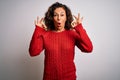Middle age brunette woman wearing casual sweater standing over isolated white background looking surprised and shocked doing ok Royalty Free Stock Photo