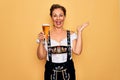 Middle age brunette woman wearing german traditional oktoberfest dress drinking glass of beer very happy and excited, winner Royalty Free Stock Photo