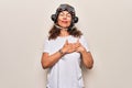 Middle age brunette woman wearing goggles and retro aviator leather hat over white background smiling with hands on chest, eyes Royalty Free Stock Photo