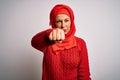 Middle age brunette woman wearing muslim traditional hijab over isolated white background Punching fist to fight, aggressive and