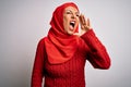 Middle age brunette woman wearing muslim traditional hijab over isolated white background shouting and screaming loud to side with Royalty Free Stock Photo