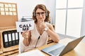 Middle age brunette woman wearing operator headset holding call me banner looking confident at the camera smiling with crossed Royalty Free Stock Photo