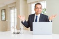 Middle age business man working with computer laptop clueless and confused expression with arms and hands raised Royalty Free Stock Photo