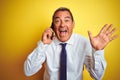 Middle age businessman talking on the smartphone over isolated yellow background very happy and excited, winner expression Royalty Free Stock Photo