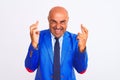 Middle age businessman wearing suit standing over isolated white background gesturing finger crossed smiling with hope and eyes