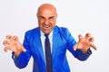 Middle age businessman wearing suit standing over isolated white background smiling funny doing claw gesture as cat, aggressive