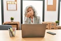 Middle age businesswoman sitting on desk working using laptop at office tired rubbing nose and eyes feeling fatigue and headache Royalty Free Stock Photo