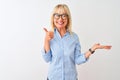 Middle age businesswoman wearing elegant shirt and glasses over isolated white background Showing palm hand and doing ok gesture Royalty Free Stock Photo