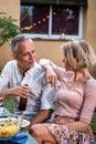 Middle age caucasian couple talk during barbecue garden dinner party outdoors.