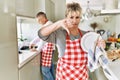 Middle age caucasian couple wearing apron washing dishes at home with angry face, negative sign showing dislike with thumbs down, Royalty Free Stock Photo