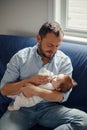Middle age Caucasian father feeding newborn baby from bottle with milk. Man parent holding rocking child on his hands. Authentic Royalty Free Stock Photo