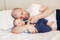 Middle age Caucasian father in white t-shirt lying in bed with newborn baby son Royalty Free Stock Photo
