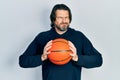Middle age caucasian man holding basketball ball skeptic and nervous, frowning upset because of problem