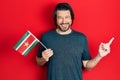 Middle age caucasian man holding suriname flag smiling happy pointing with hand and finger to the side