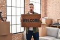 Middle age caucasian man holding welcome doormat at new home afraid and shocked with surprise and amazed expression, fear and Royalty Free Stock Photo