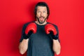 Middle age caucasian man using boxing gloves afraid and shocked with surprise and amazed expression, fear and excited face Royalty Free Stock Photo