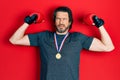 Middle age caucasian man wearing first place medal on boxing competition in shock face, looking skeptical and sarcastic, surprised Royalty Free Stock Photo