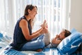 Middle age Caucasian mother playing with boy toddler son. Mom and child baby having fun on bed in bedroom at home. Happy authentic Royalty Free Stock Photo